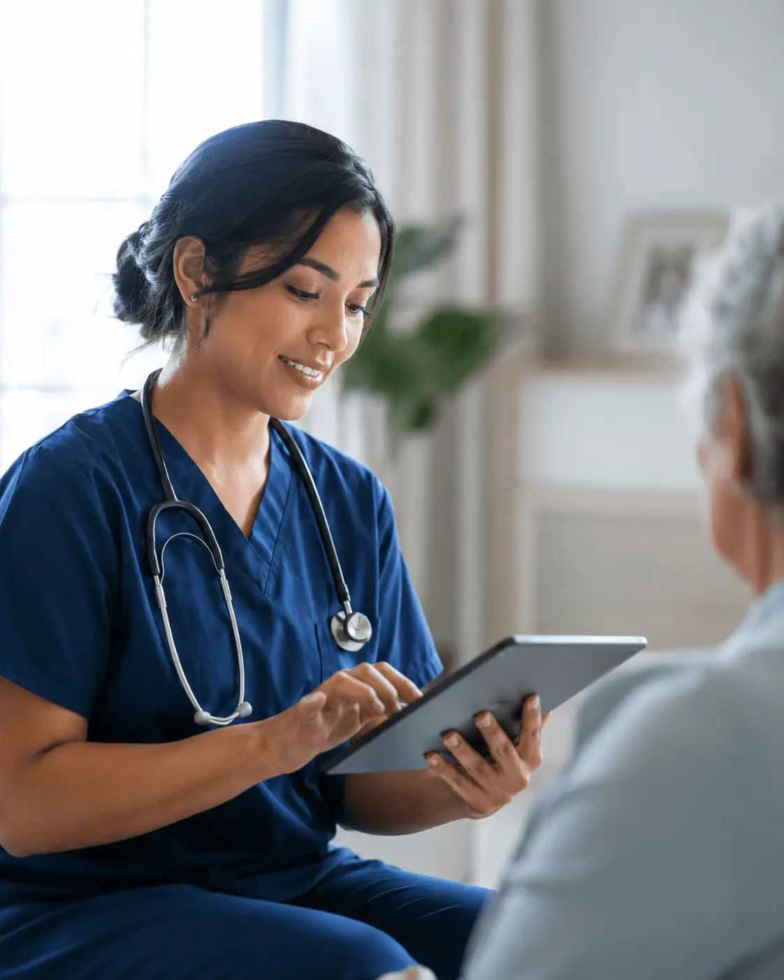 Hospice nurse using a tablet for AI-assisted clinical documentation during a patient visit